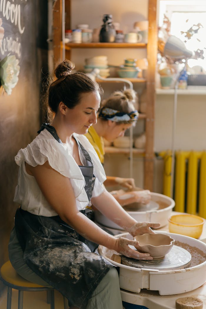 Two women creating handmade pottery in a cozy indoor studio setting.